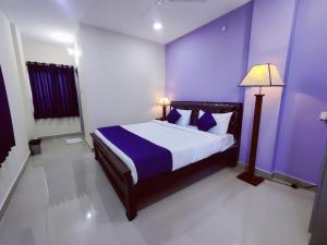 a bedroom with a large bed with purple walls at Hotel Prime Classic in Shamshabad