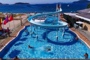 a swimming pool with a slide in the water at Kampaoh Bayona Playa in Baiona