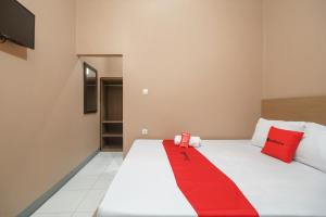 a room with a bed with a red blanket on it at RedDoorz Syariah @ Bulak Kapal in Bekasi