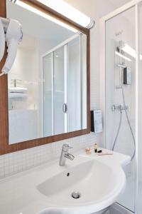 La salle de bains est pourvue d'un lavabo blanc et d'un miroir. dans l'établissement Campanile Hotel Nice Centre Acropolis, à Nice