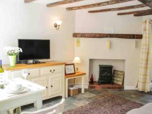 uma sala de estar com televisão e lareira em Charming 1-Bed Cottage located in Ironbridge em Ironbridge
