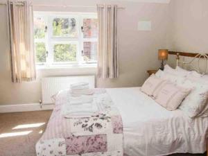 a bedroom with a bed with white sheets and a window at Charming 1-Bed Cottage located in Ironbridge in Ironbridge