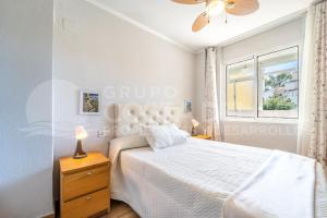 a white bedroom with a bed and a window at Apartamento Buen Consejo in Torremolinos