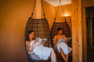 un homme et une femme assis dans une balançoire dans l'établissement Dolomitenhotel Weisslahnbad, à Tires