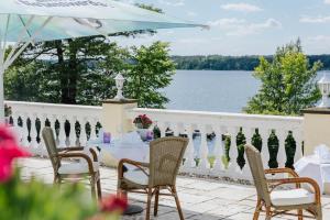 einen Tisch und Stühle auf einem Balkon mit Blick auf das Wasser in der Unterkunft Hotel Resort Märkisches Meer in Diensdorf-Radlow