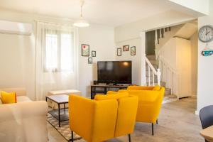 ein Wohnzimmer mit gelben Stühlen und einem Flachbild-TV in der Unterkunft Fully Furnished and Stylish Villa in Izmir in Izmir