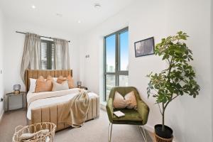 a bedroom with a bed and a chair and a plant at Livestay-Luxury London Penthouse with Enviable Views in London