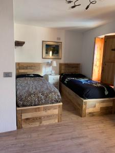 1 dormitorio con 2 camas y mesa con lámpara en Les Chemines, en La Thuile