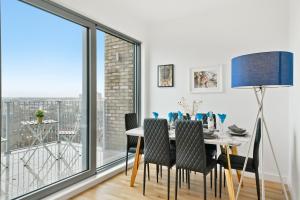 a dining room with a table and chairs and a large window at Livestay-Luxury London Penthouse with Enviable Views in London