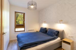 um quarto com uma cama com lençóis azuis e uma janela em Nautikka Park em Krynica Morska
