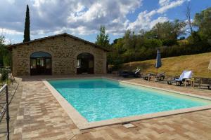 a swimming pool in front of a stone house at Agriturismo Ca'Mazzetto in Valfabbrica