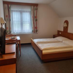 a hotel room with a bed and a desk and a window at Gasthof Kögerlwirt in Göstling an der Ybbs