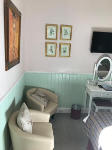 Zimmer mit 2 Stühlen, einem Schreibtisch und einem Spiegel in der Unterkunft Blair Villa South in Oban