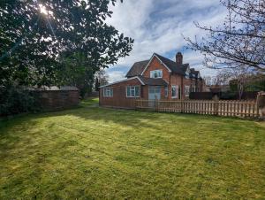 a brick house with a fence in a yard at Wheelbarrow Cottage in Bengeworth