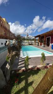 a swimming pool with a statue next to a building at Vila Feliz - Chalés completos - ideal para famílias in Serra de São Bento