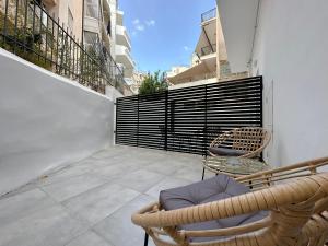 uma varanda com uma cadeira de vime e uma mesa e cadeiras em Santa Barbara I1 Elegance 73sqm apt in Nea Smirni em Atenas