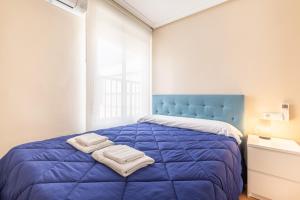 sypialnia z niebieskim łóżkiem i ręcznikami na nim w obiekcie Penthouse Ancla 562 Levante Beach w mieście Benidorm