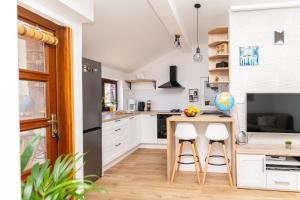 a kitchen with white cabinets and a table and stools at Apartment Gac in Cavtat