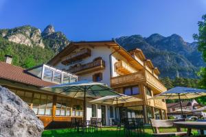 a building with tables and umbrellas in front of it at Dolomitenhotel Weisslahnbad in Tires