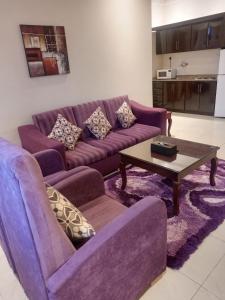 Sala de estar con 2 sofás morados y mesa de centro en Nawara Hotel, en Riad