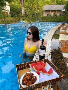 kobieta w basenie z butelką wina i arbuzem w obiekcie Queen's Homestay Ba Vì - Venuestay w mieście Ba Vì District