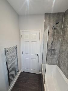 uma casa de banho com um chuveiro e uma porta branca em APARTMENT in BARNSLEY CENTRAL em Barnsley