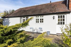 een wit huisje met 2 stoelen en een tafel bij The Willow Studio - peaceful retreat near Whitstable seaside in Kent