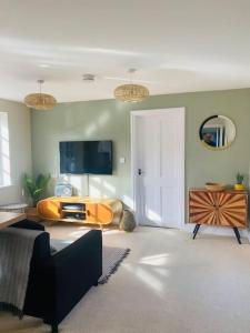 een woonkamer met een bank en een flatscreen-tv bij The Willow Studio - peaceful retreat near Whitstable seaside in Kent