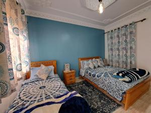 2 camas en un dormitorio con paredes azules en Diafa, en Tánger