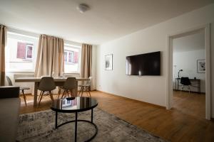 een woonkamer met een tafel en een tv aan de muur bij Old Town Apartment 2 rooms/baths in Düsseldorf