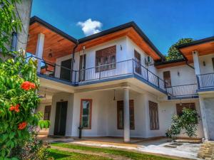 a large white house with a balcony at Elepath Lodge- Pinnawala in Pinnawala