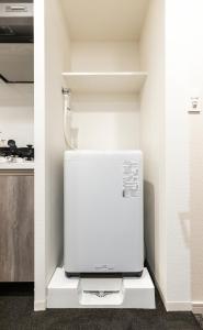 a kitchen with a white refrigerator in a room at Apartment Hotel 11 Kuromon in Osaka