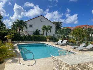 einen Pool mit einem Tisch und Stühlen neben einem Haus in der Unterkunft Nanpa, Luxury Family Three Bed Villa, St James West coast, Private pool in Saint James