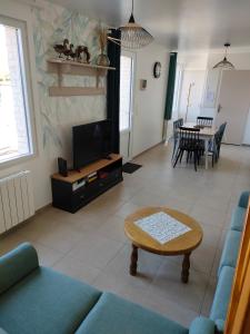een woonkamer met een bank en een tv bij L'intemporelle in Le Crotoy
