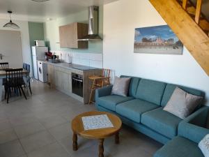 a living room with a blue couch and a kitchen at L'intemporelle in Le Crotoy