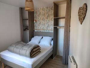 a small bedroom with a bed with white sheets at L'intemporelle in Le Crotoy
