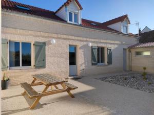 a wooden picnic table in front of a building at L'intemporelle in Le Crotoy