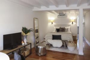 Cette chambre comprend un lit avec un miroir et une télévision. dans l'établissement Chic Urban Retreat at Downtown with Balcony & Views, 5th-floor no lift, à Lisbonne