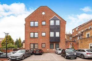 a brick building with cars parked in a parking lot at The Courtyard 2 Bedroom Apartments in Central Windsor with Parking in Windsor