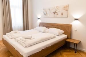 a bed with white sheets and pillows in a room at Nadland Apartments B61 in Vienna