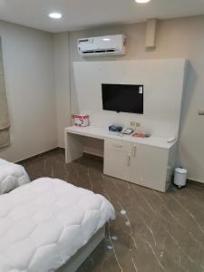 a bedroom with a bed and a desk with a tv at Marina H in Sohar