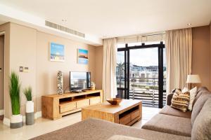 Una sala de estar con un sofá y un televisor. en Modern Beachfront Eden on the Bay 210- 2 bedroom, 2 bathroom, en Bloubergstrand