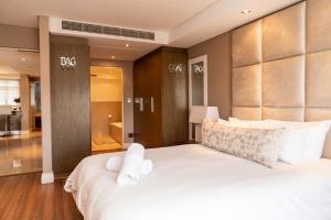 Un dormitorio con una gran cama blanca con almohadas blancas. en Modern Beachfront Eden on the Bay 210- 2 bedroom, 2 bathroom, en Bloubergstrand