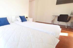 - un lit blanc avec des oreillers bleus dans l'établissement Modern 3Bedroom Duplex W/Pool by LovelyStay, à Alcantarilha