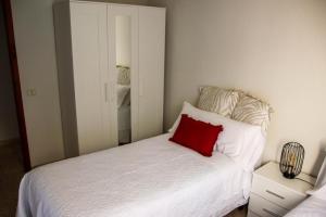 a bedroom with a white bed with a red pillow at MI CAPRICHO in Santa Cruz de la Palma