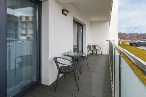 balkon z krzesłami i stołem w budynku w obiekcie Apartamenty Sunset Resort by Renters w Grzybowie