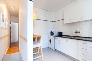 een keuken met witte kasten en een wasmachine en droger bij Chic Urban Apartment at Downtown with a Sunny Balcony! in Lissabon