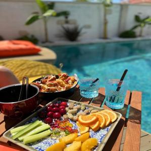 a tray of fruit and vegetables on a table next to a pool at My Angels Alaçatı in Alaçatı