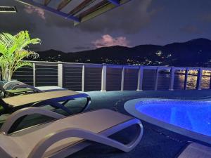 balcón con piscina y 2 sillas en Drake Seaside Studio Apartments en Bel Ombre