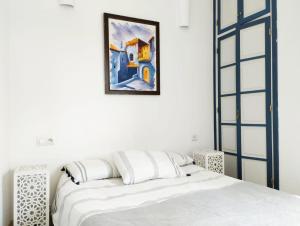 a bedroom with a bed and a painting on the wall at Maison Médina, terrasse panoramique, vue mer in Tangier
